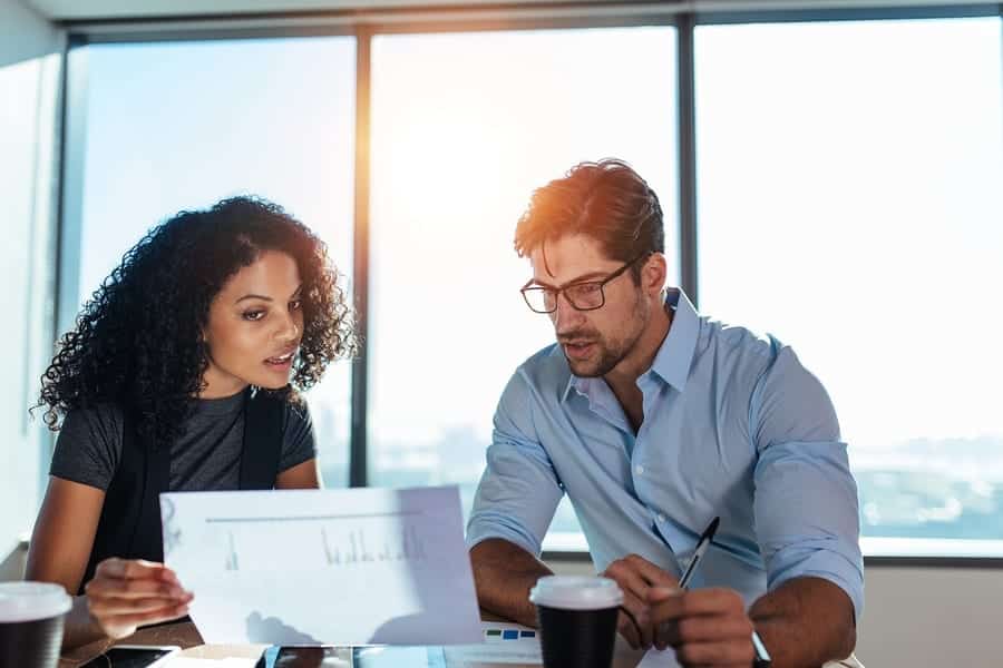 Young woman entrepreneur showing a paper to her business partner while discussing business plans.