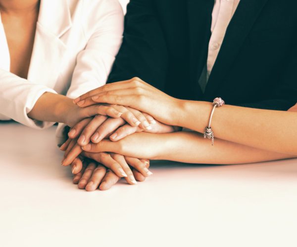 Businessmen and businesswomen joining hands in group meeting at multicultural office room showing teamwork, support and unity in business. Diversity workplace and corporate people working concept. uds
